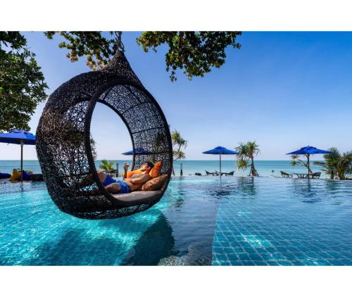 a group of people laying in a swing in a pool at Nirvana Beach Resort, Koh Lanta SHA Extra Plus in Ko Lanta
