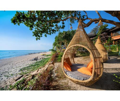 a hammock hanging from a tree on a beach at Nirvana Beach Resort, Koh Lanta SHA Extra Plus in Ko Lanta