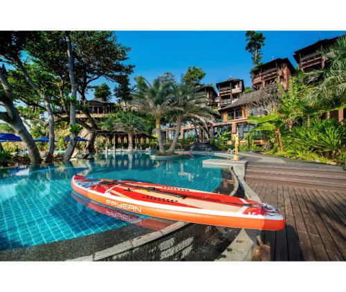 a red boat sitting next to a swimming pool at Nirvana Beach Resort, Koh Lanta SHA Extra Plus in Ko Lanta