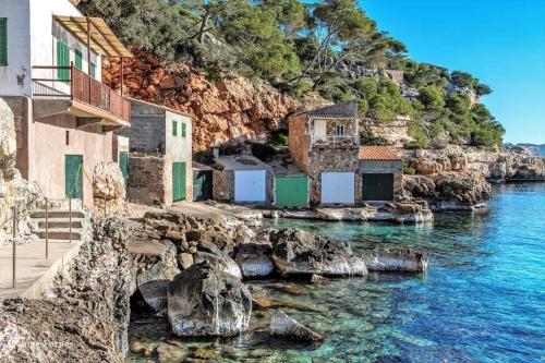 a group of houses on the shore of the water at Ca Na Marina in Cala Llombards