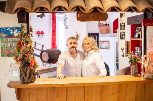 a man and a woman standing at a counter at Hotel La Bonne Auberge in Saint-Martin-Vésubie