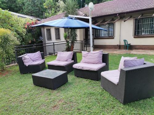un grupo de sillas y un paraguas en un patio en Jackies Guest House, en Durban