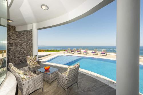a villa with a swimming pool and a patio with chairs at Elite Sea View Villa in Pomos