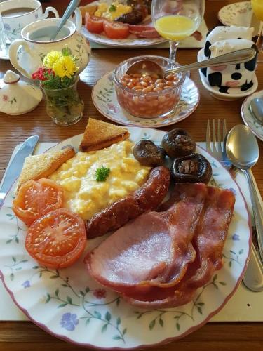 a breakfast plate with bacon eggs sausage and tomatoes at Dunscar Farm Bed & Breakfast in Castleton