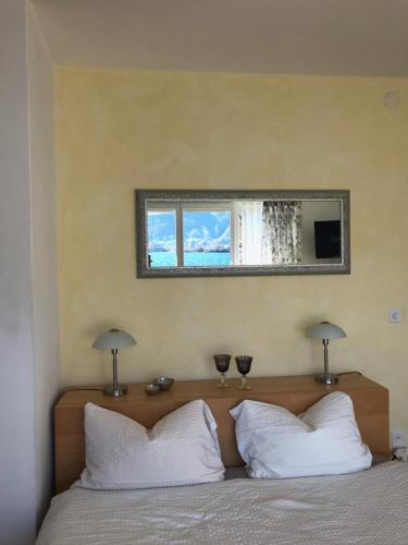a mirror above a bed with two wine glasses on it at Casa Conti al Lago in Ronco s/Ascona - Porto Ronco