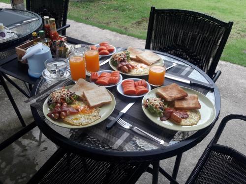 een tafel met borden vol eten en sinaasappelsap bij Phuket Sirinapha Resort in Nai Yang Beach