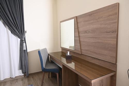 a desk with a mirror and a blue chair at RAWND Hotel Apartments in Dammam