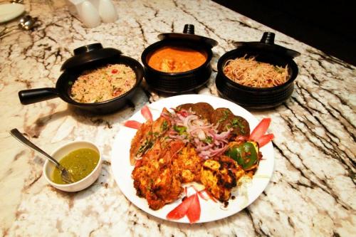 une table avec une plaque de nourriture et deux pots de nourriture dans l'établissement Playotel Inn Golden Treat, à Indore
