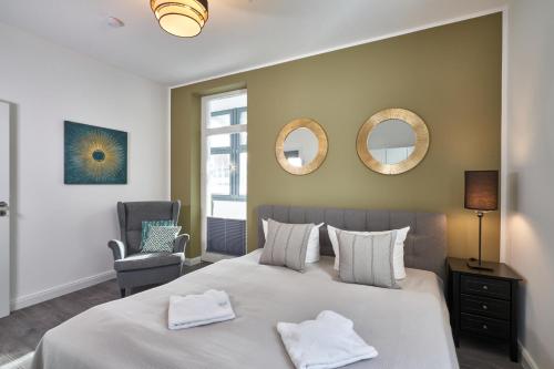 a bedroom with a bed and a chair and mirrors at Haus am Meer Sellin App 5 und 6 by Meine Ferienzeit in Ostseebad Sellin