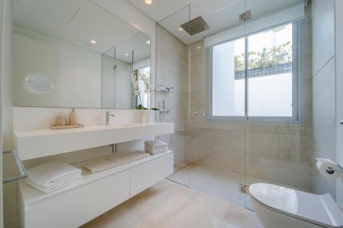 a white bathroom with a sink and a shower at Holiday in ground floor apartment in Marbella Club Hills, Benahavis in Benahavís