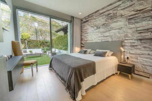 1 dormitorio con cama y pared de piedra en Holiday in ground floor apartment in Marbella Club Hills, Benahavis, en Benahavís