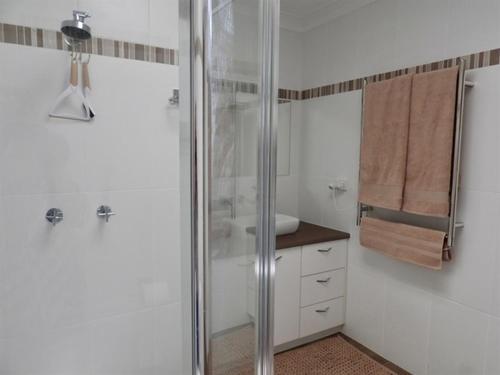 Un baño blanco con ducha y lavabo. en Denham's Beachfront, en Sunshine Bay