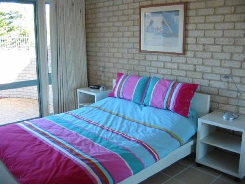 a bedroom with a bed with colorful sheets and a window at Sandy Place on Long Beach in Long Beach