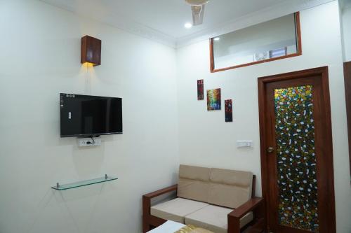 a living room with a tv and a chair and a door at Classia Suites in Bengaluru