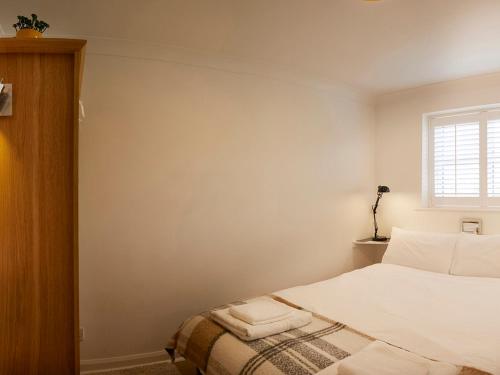 a bedroom with a bed with white sheets and a window at Rosewood Cottage in Bridlington