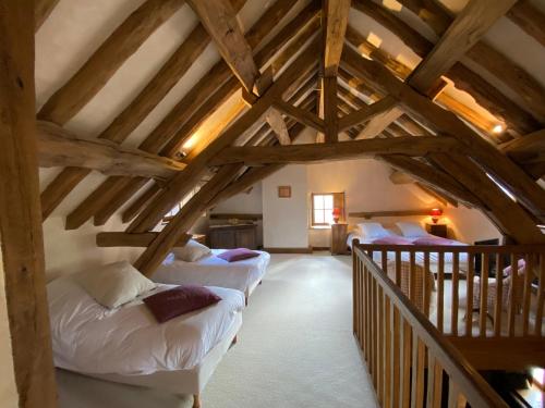 a attic room with white beds and wooden beams at Le Hameau de Barboron in Savigny-lès-Beaune