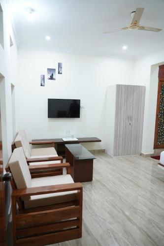 a living room with chairs and a flat screen tv at Classia Suites in Bengaluru