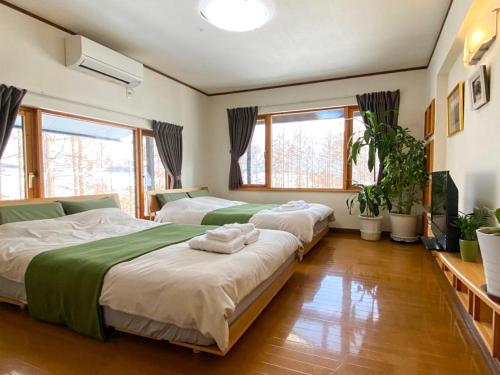 two beds in a room with windows at Ritz Garden Niji in Biei