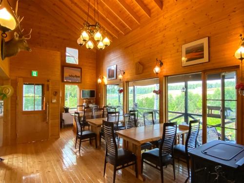 a dining room with tables and chairs and windows at Ritz Garden Niji in Biei