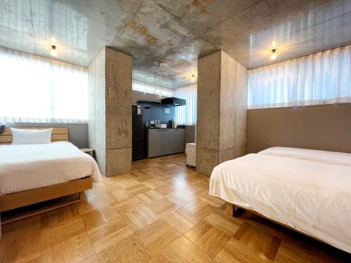 東京的住宿－PRISM INN OGU，客房内设有两张床,铺有木地板,设有窗户。