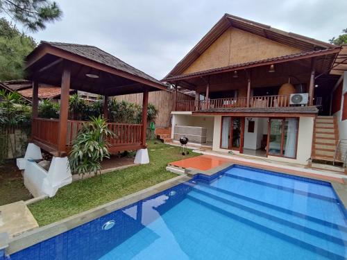 uma villa com piscina em frente a uma casa em Villa Etnik Syariah em Bandung