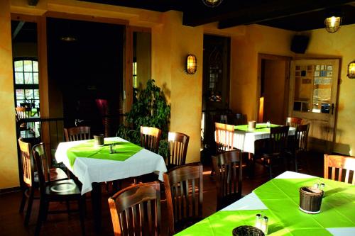 un restaurant avec des tables, des chaises et un tissu de table vert dans l'établissement Ferienwohnung A Gästehaus Mühlenstein, à Bad Sülze