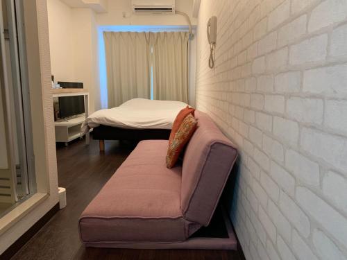ein kleines Zimmer mit einem Sofa und einem Bett in der Unterkunft Exsaison Shirokita 705 in Osaka