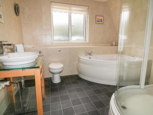 a bathroom with a tub and a toilet and a sink at Lodge 22, Bodmin Holiday Park, Cornwall in Lanivet