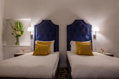 two beds with yellow pillows in a hotel room at Hotel Gamla Stan, BW Signature Collection in Stockholm