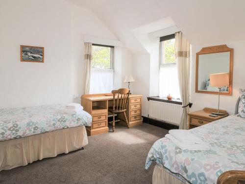 a bedroom with two beds and a desk and a mirror at St Duthus House in Stornoway