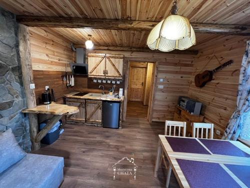 a kitchen in a log cabin with a table and a sink at Bieszczady Noclegi "Muzyczna Chata" in Olszanica