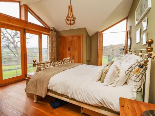 a bedroom with a large bed and large windows at Ty Gwyn Cottage in Llysfaen