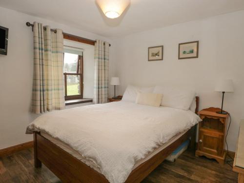 ein Schlafzimmer mit einem Bett mit weißen Laken und einem Fenster in der Unterkunft Tanner Croft Cottage in Ambleside