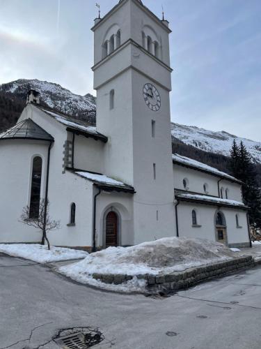 a white church with a clock tower in the snow at Modern Täsch Apartment with Free Parking in Täsch