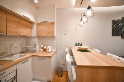a kitchen with a wooden counter top and white cabinets at Balkan Hill Zlatibor in Zlatibor