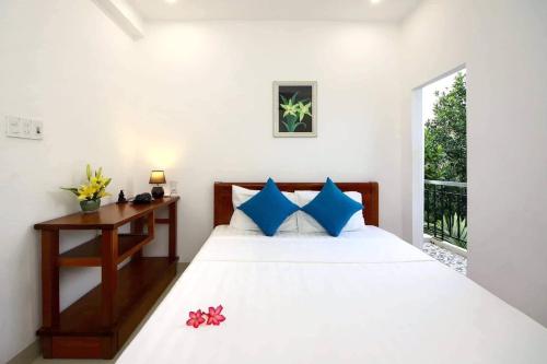 een slaapkamer met een bed, een bureau en een raam bij Cherry Garden Homestay in Hội An