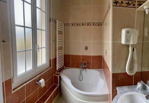 a bathroom with a bath tub and a sink at Hotel Le Normand in Houlgate