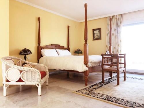 sypialnia z łóżkiem z baldachimem i 2 krzesłami w obiekcie Beautiful, Bright and Spacious Duplex in Marbella w mieście Estepona