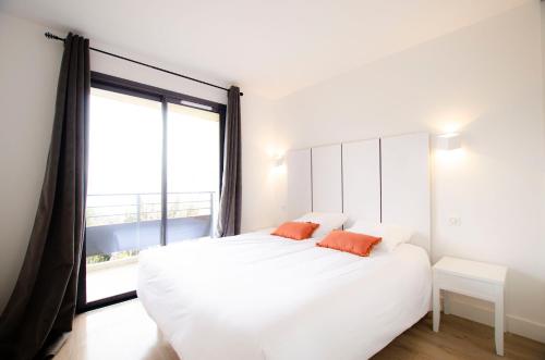a bedroom with a white bed with two orange pillows at La Perle d'Eze - Aparthotel in Èze