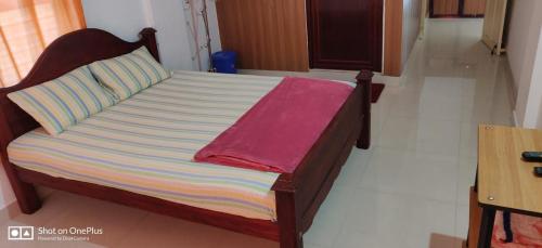 a bed with a wooden frame and a pink towel on it at Wintervalley homestay in Vayittiri