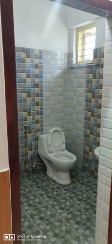 a bathroom with a toilet and a tiled floor at Wintervalley homestay in Vayittiri