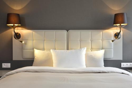 a bedroom with a large white bed with two lamps at Martin's All Suites in Louvain-la-Neuve