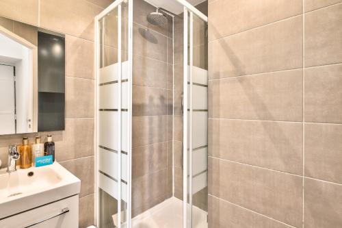 une douche avec une porte vitrée dans une salle de bain dans l'établissement 04 Best Flat Montorgeuil 3, à Paris