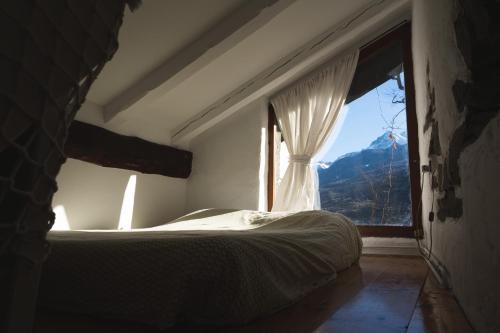 a bedroom with a bed and a large window at Cascina Des Religieuses in Aosta