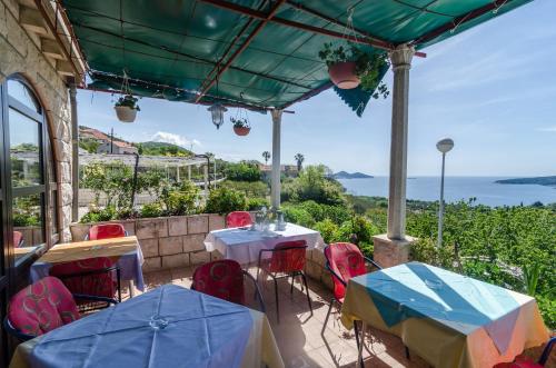 a patio with tables and chairs and a view of the ocean at Guesthouse Moretic in Orasac