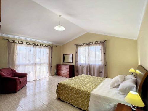 1 dormitorio con 1 cama, 1 silla y ventanas en Vila Feliz, en Paul do Mar