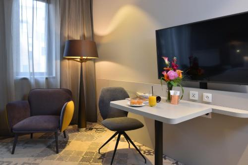 a hotel room with a table and chairs and a tv at Martin's All Suites in Louvain-la-Neuve