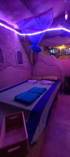 Jungle river humbhaha hostel في كاتاراغاما: سرير في غرفة مع أضواء أرجوانية