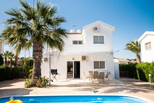 a white house with a palm tree and a swimming pool at Protaras View Villas in Protaras