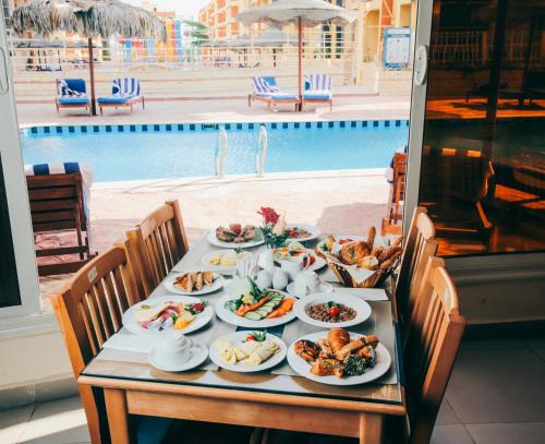 a table with plates of food and a pool at Retal View North Coast Aqua Park in El Alamein